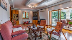 A spacious living room with a wooden floor, a large window, and a dining area with a table and chairs. - Amazing home in Medulin (Medulin)