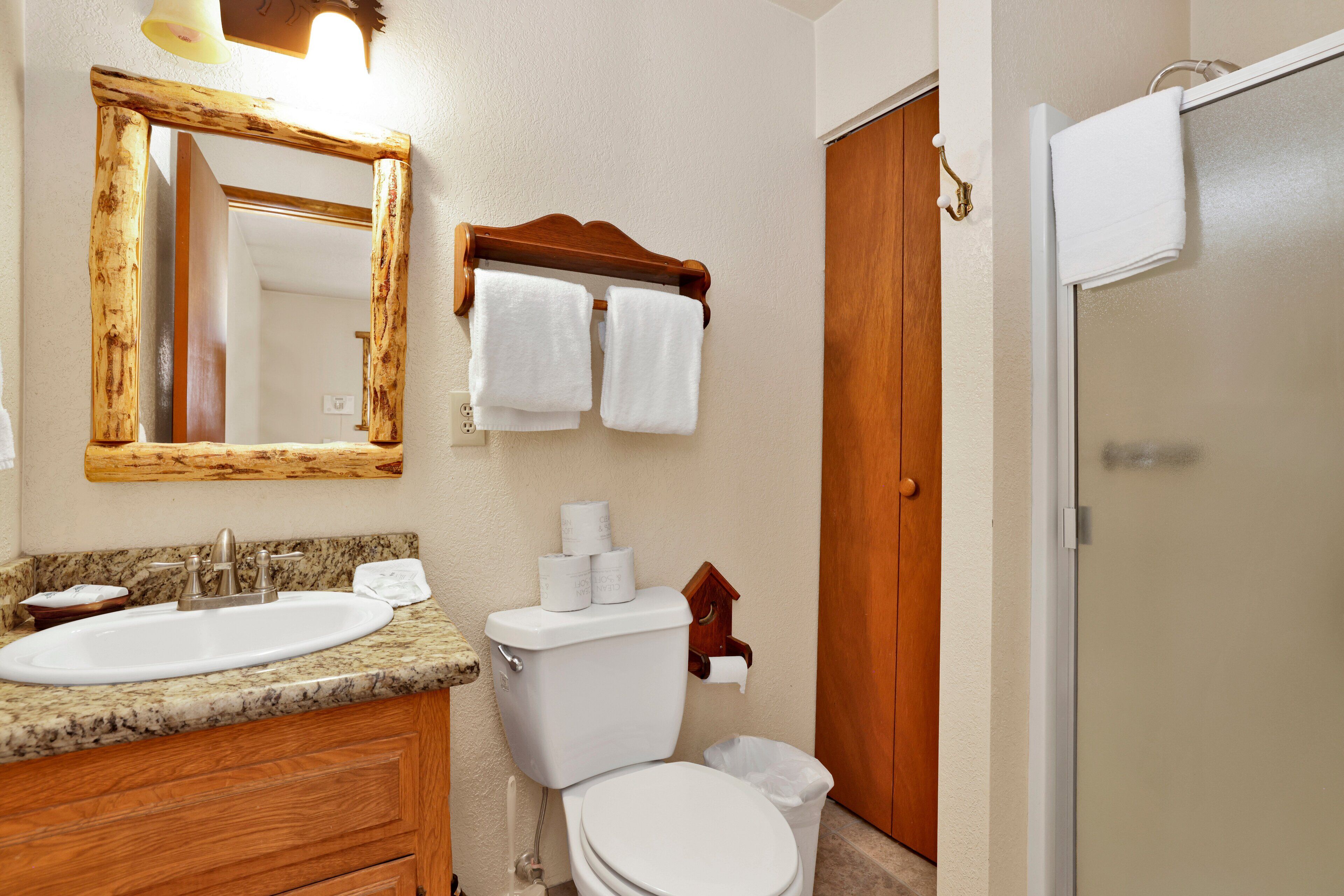 A bathroom with a sink, toilet, and mirror.