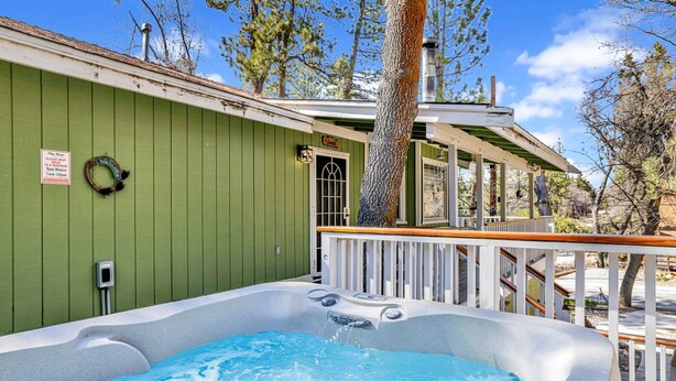 A hot tub on a deck with a green wall and a sign that says "Please keep to a minimum noise 7am-10pm". - Good Times #1295 (Big Bear City)