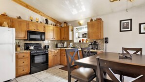 A kitchen with wooden cabinets, a stove, a microwave, and a dining table with chairs. - Good Times #1295 (Big Bear City)