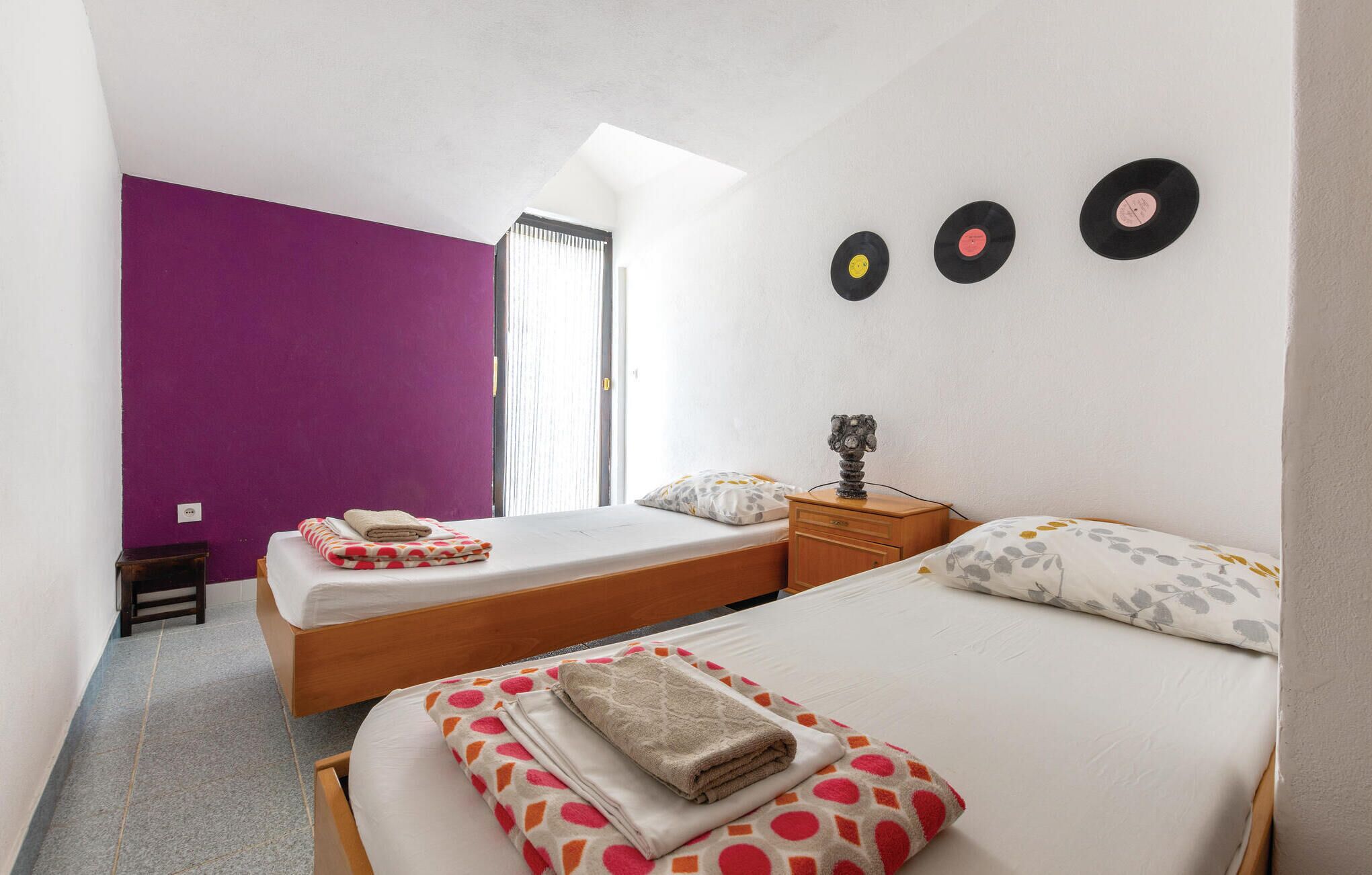 Una camera da letto con due letti, una finestra e tre dischi in vinile appesi al muro.