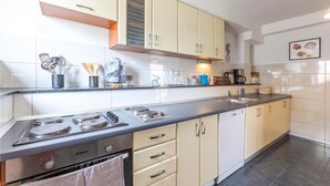 Una cocina moderna con armarios color beige, una estufa de acero inoxidable y una encimera negra.