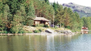 A cabin by a lake surrounded by trees.