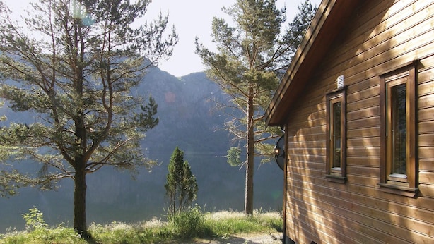 A cabin with a wooden exterior, a window, and a view of a mountain range.
