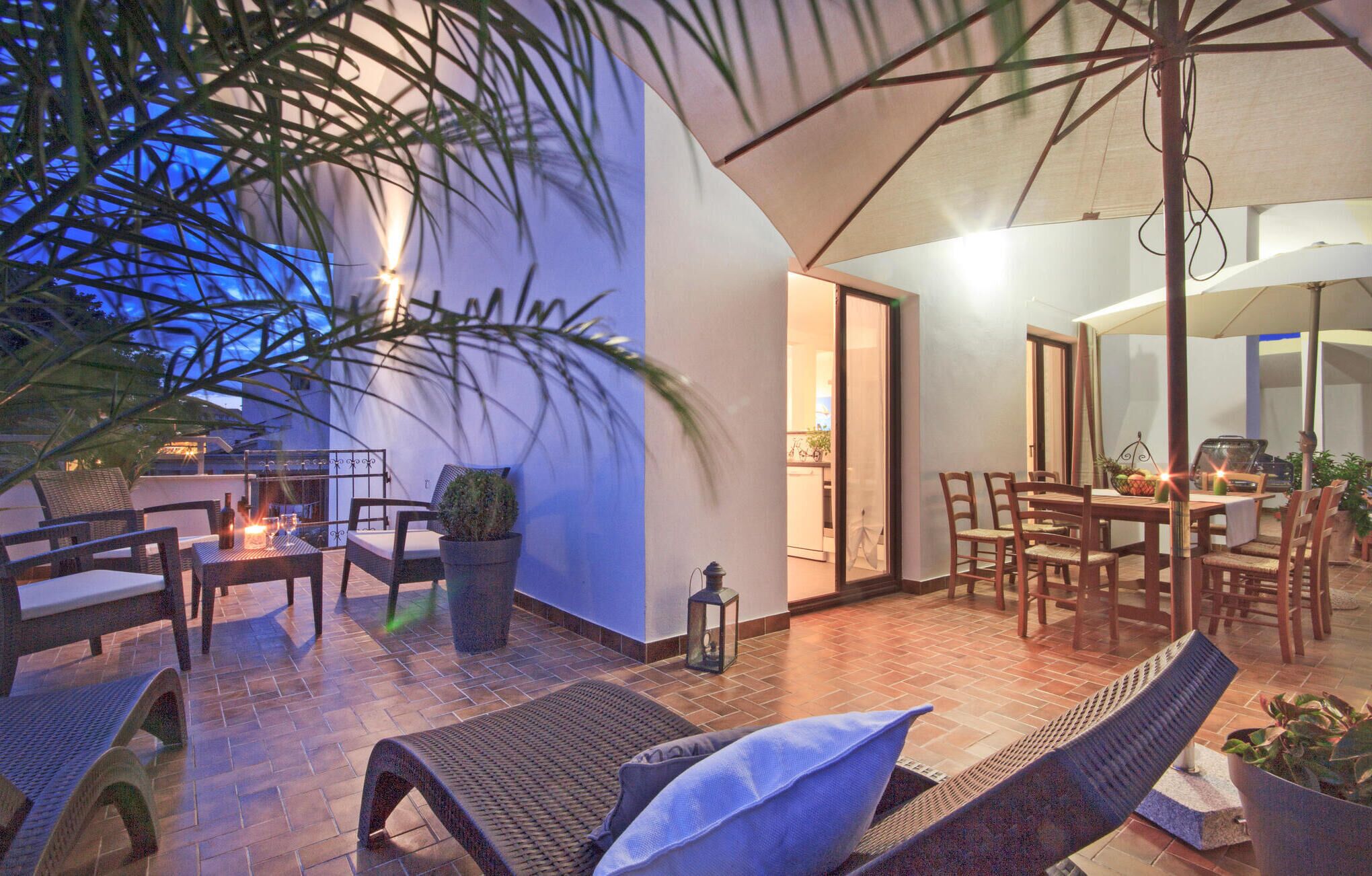 An outdoor patio area with wicker furniture, a dining table, and potted plants.