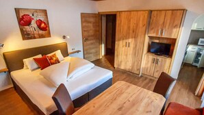 Une chambre d’hôtel avec un lit, une table en bois, une télévision et une kitchenette.