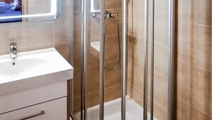Une salle de bain avec une douche à parois de verre, un lavabo blanc et un miroir au-dessus.