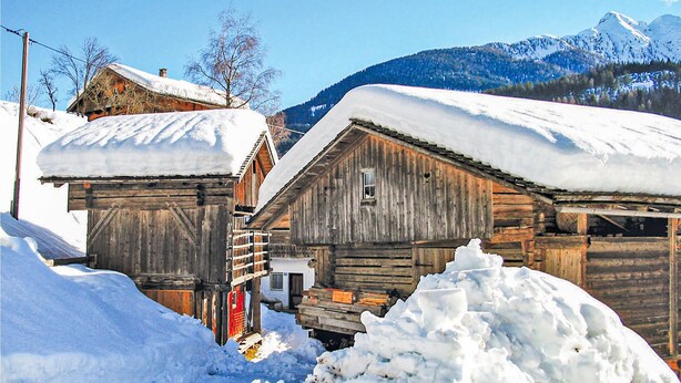 A rustic wooden building with a snow-covered roof, surrounded by snow. - Ferienhaus in Maria Luggau (Maria Luggau)