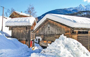 Un edificio rústico de madera con techo nevado, rodeado de nieve.