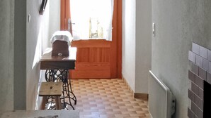 A narrow hallway with a sewing machine, a small table, and a wooden door leading to a bright room. - Ferienhaus in Maria Luggau (Maria Luggau)