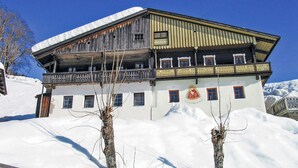 A two-story building with a balcony, surrounded by snow. - Ferienhaus in Maria Luggau (Maria Luggau)