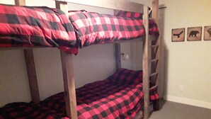 A bunk bed with red and black checkered bedding in a room with a ladder, a door, and three animal-themed wall decorations. - Fantastic  Spacious Family Condo (Kelowna)
