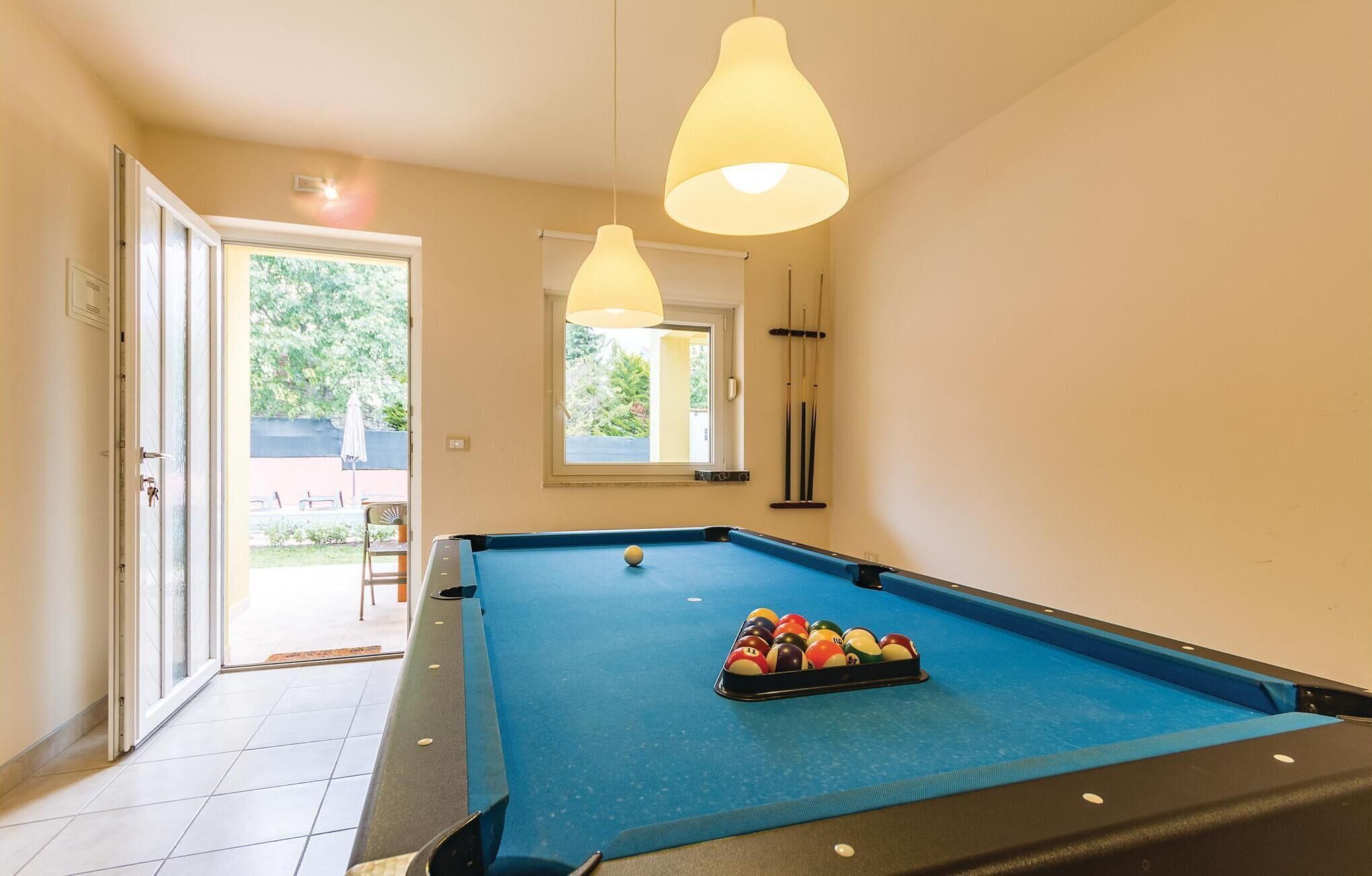 A pool table with a blue felt surface, a rack of billiard balls, and two hanging lamps.