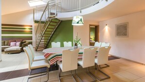 A dining area with a table set for six, surrounded by white chairs, a staircase, and a green accent wall. - Amazing home in Medulin (Medulin)