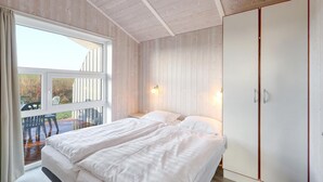 A bedroom with two beds, a large window, and a wardrobe. - Friedrichskoog-Strandpark 9 (Friedrichskoog)