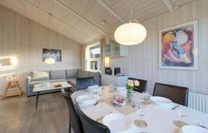 A dining area with a round table set for four, a grey sofa, and a large abstract painting on the wall. - Friedrichskoog-Strandpark 9 (Friedrichskoog)