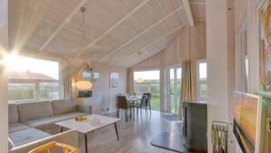 A spacious living area with a large sofa, a dining table, and a kitchen area with a refrigerator. - Friedrichskoog-Strandpark 9 (Friedrichskoog)