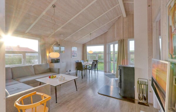 A spacious living area with a large sofa, a dining table, and a kitchen area with a refrigerator. - Friedrichskoog-Strandpark 9 (Friedrichskoog)