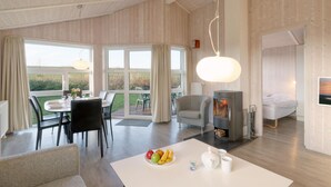 A spacious living area with a dining table set for two, a sofa, and a fireplace. - Friedrichskoog-Strandpark 9 (Friedrichskoog)