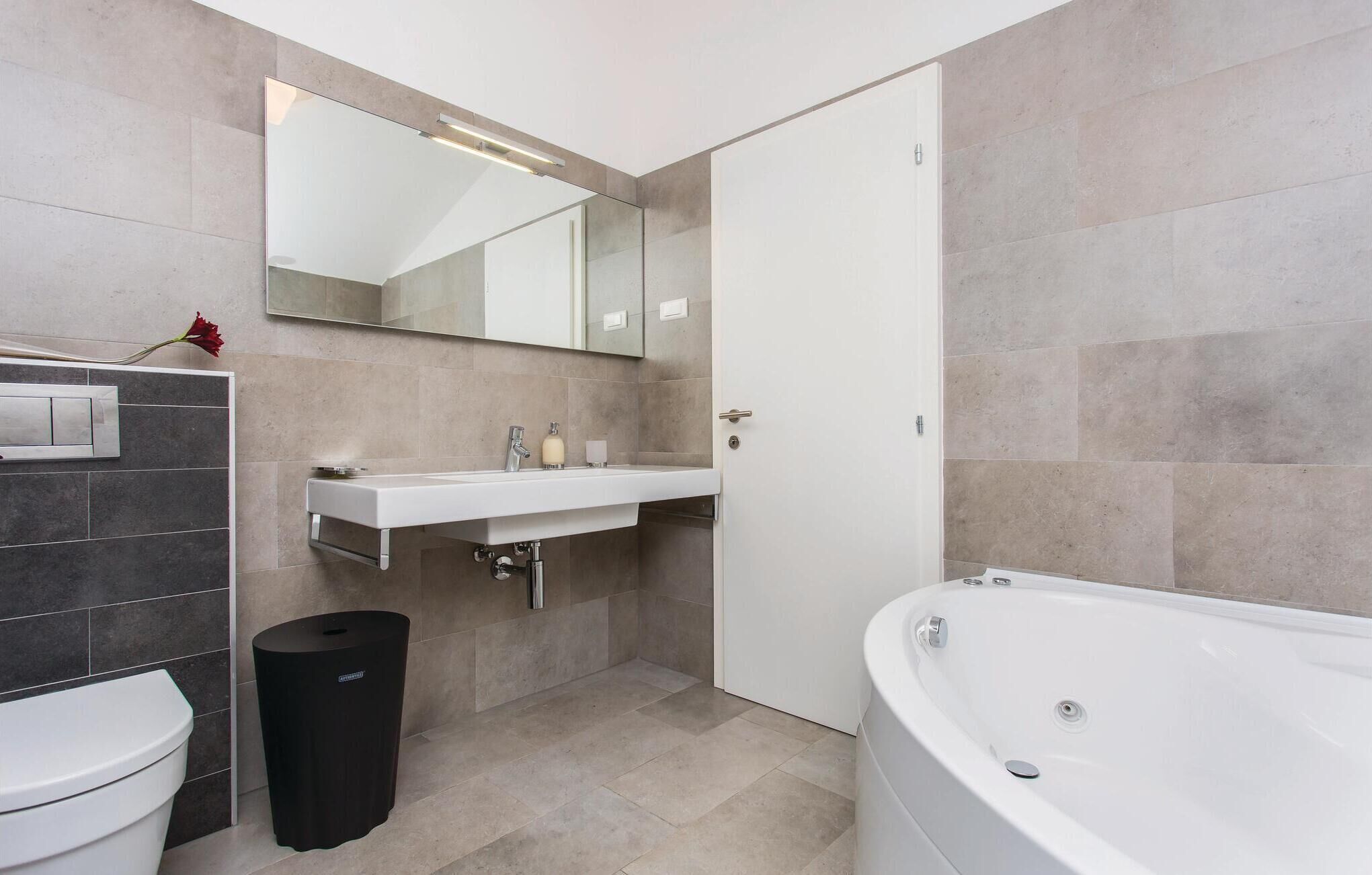 Une salle de bain moderne équipée de toilettes, d’un lavabo, d’un miroir et d’une baignoire.