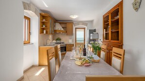 Une cuisine moderne avec des meubles en bois, une table à manger dressée pour le repas, et une vue sur l’extérieur.