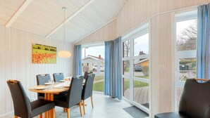 Un coin repas avec une table et des chaises en bois, un tableau au mur et une vue sur l’extérieur.