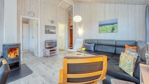 Un salon chaleureux avec une cheminée, un canapé, une table à manger et un téléviseur.