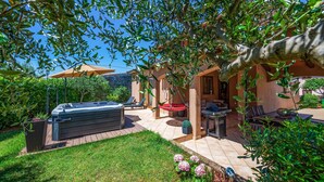 Un espace patio comprenant un jacuzzi, des sièges d’extérieur et un mur en pierre.