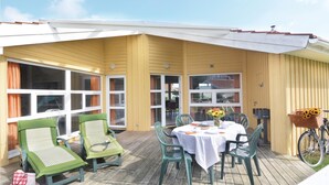 A covered outdoor patio with a table and chairs, a bicycle, and a basket of flowers. - Freibeuterweg 6 - Dorf 6 (Travemünde-Priwall)