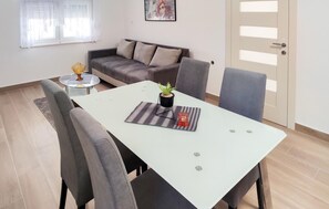 Un salon moderne comprenant un canapé, une table à manger avec des chaises, une petite table d’appoint et une plante en pot.
