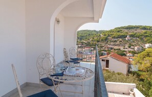 Un balcon avec une table ronde et des chaises, donnant sur un village pittoresque.