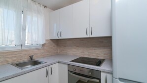 Una cocina con armarios blancos, encimera de granito, pileta de acero inoxidable y horno empotrado.