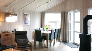 A modern living room with a dining area, wooden walls, a large window, and a fireplace. - Beach front home in Schönhagen (Schönhagen)