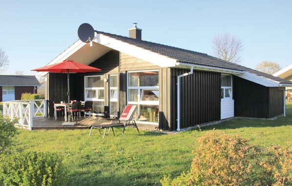 A modern house with a covered patio, a satellite dish, and a red umbrella.