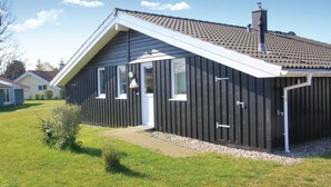 A modern single-story house with a dark exterior, white trim, and a sloped roof. - Beach front home in Schönhagen (Schönhagen)