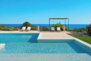 A swimming pool with clear blue water, surrounded by lounge chairs and a pergola. - Casa Carol (Bianco) - Villa with shared pool (Scicli)