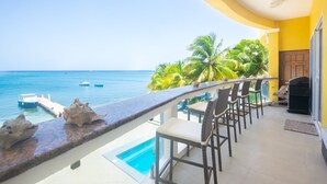 Ein Balkon mit Blick auf das Meer, einen Pool und tropische Pflanzen.