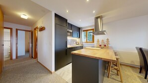 A modern kitchen with dark cabinets, a wooden island, and a built-in stove.