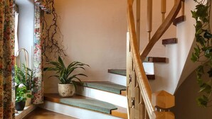 Una escalera con barandillas de madera y peldaños cubiertos de moqueta verde.