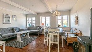 A spacious living area with a grey sofa, a dining table with chairs, and a fireplace. - 3 bedroom awesome home in Hasle (Hasle)