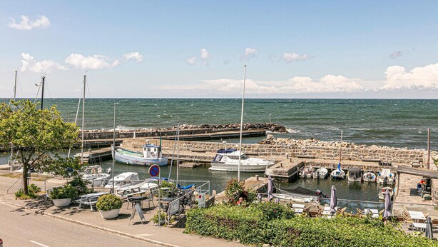 A marina with boats docked, a stone pier, and a café area with outdoor seating. - 3 bedroom awesome home in Hasle (Hasle)