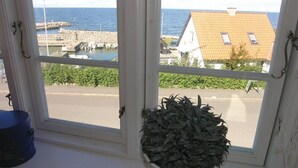 A window with a view of a harbor, a building with a tiled roof, and a potted plant on the windowsill. - 3 bedroom awesome home in Hasle (Hasle)