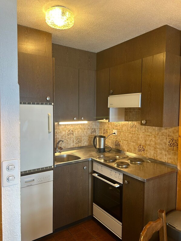 A compact kitchen with a built-in dishwasher, a stove, and a sink.