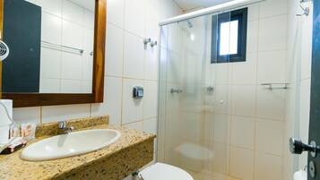 A bathroom with a granite countertop sink, a white toilet, and a glass-enclosed shower.