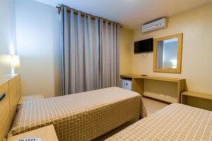 Habitación de hotel con dos camas, un escritorio, un espejo, un equipo de aire acondicionado y una lámpara.