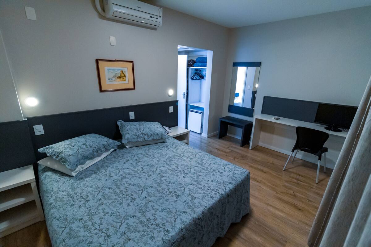 A bedroom with a bed, a desk, and a chair.