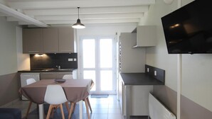 Una cocina compacta con zona de comedor, un televisor de pantalla plana montado en la pared y un ventanal que ofrece luz natural.