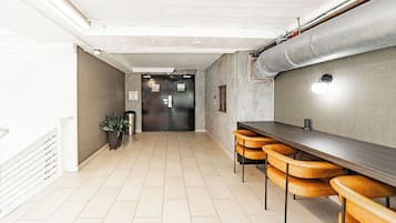 A corridor with a long table and chairs, a door with a sign, and a potted plant.