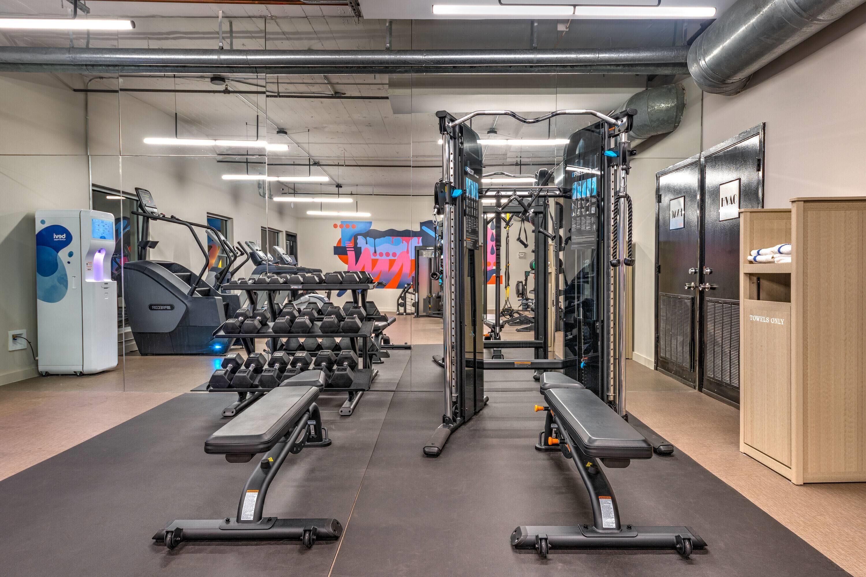A gym with treadmills, weight machines, and dumbbells.