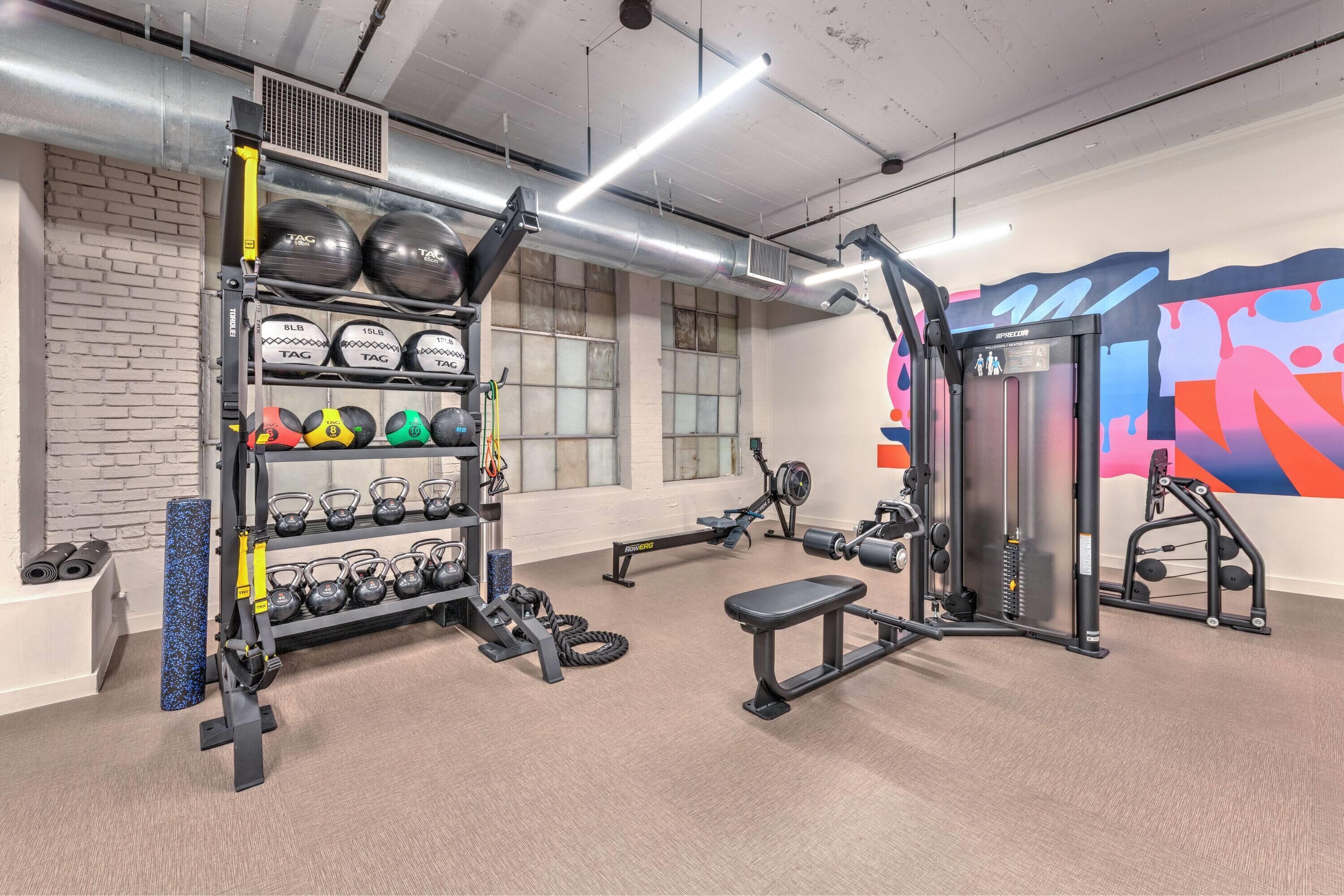 A gym with weightlifting equipment, kettlebells, and a bench.